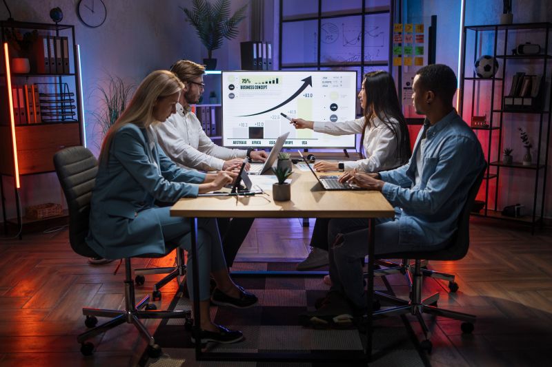 Diverse team of financial professionals analyzing business growth charts on an interactive screen