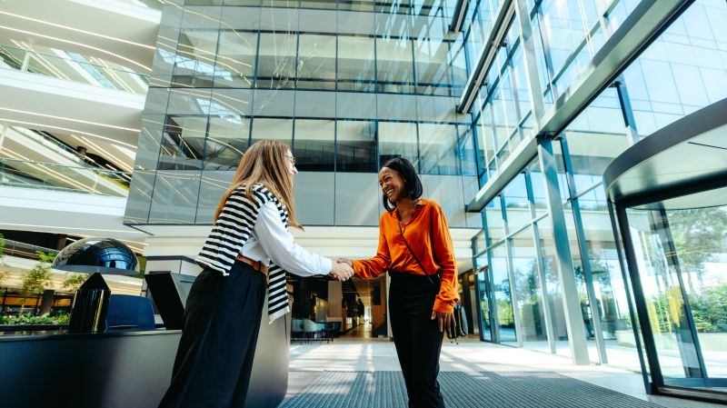 Professional greeting between colleagues in modern office lobby